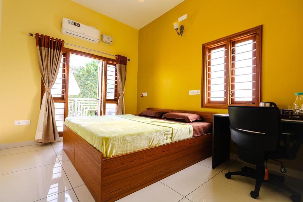 a bedroom with a bed and a desk and window at Osho Glimpse Mysore in Mysore