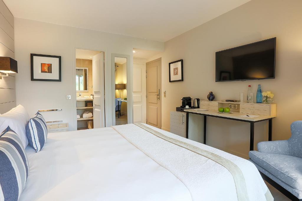 a bedroom with a large white bed and a desk at La Bastide de Biot in Biot