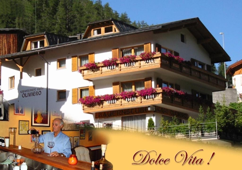a man sitting at a table in front of a building at Appartements Hotel-Garni Dolce Vita in Samnaun