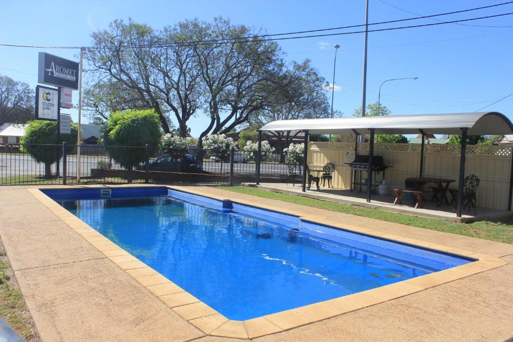 een blauw zwembad in een tuin met een paviljoen bij Aromet Motor Inn in Temora