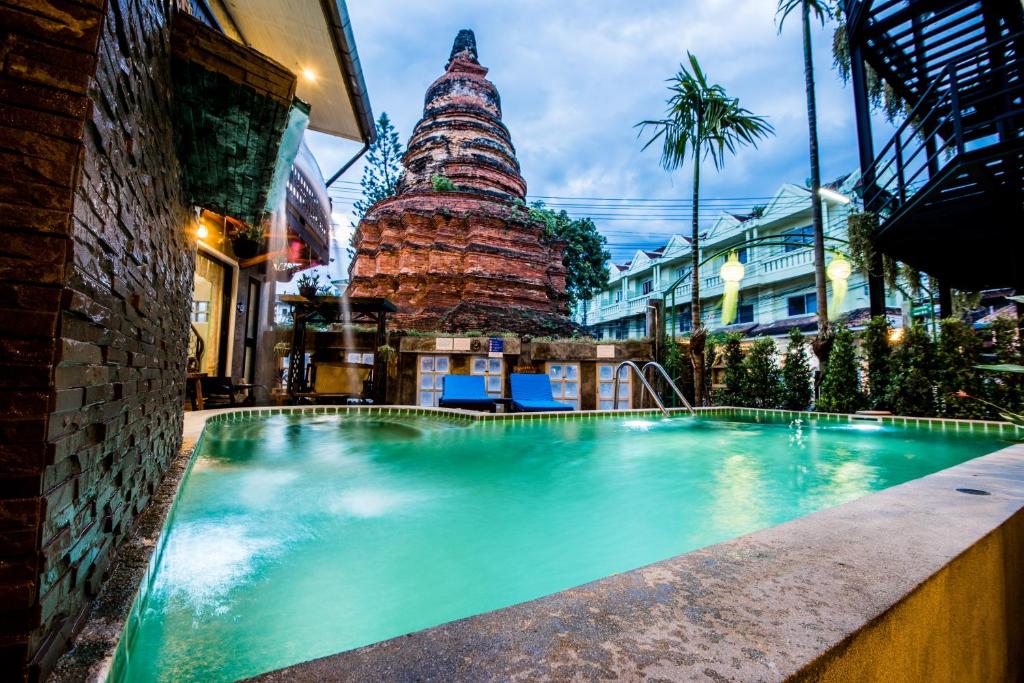 una piscina frente a un edificio con torre en Chedi Home -SHA Extra Plus, en Chiang Mai