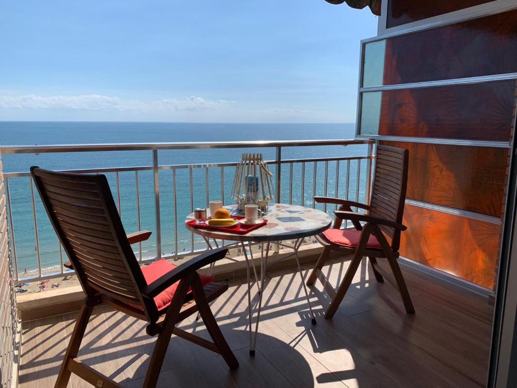 uma mesa e duas cadeiras numa varanda com o oceano em Apartamento con vistas al mar primera linea de playa del Postiguet em Alicante