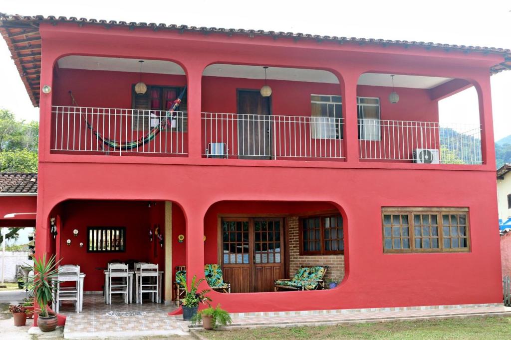 a red house with a balcony and tables and chairs at KR Hostel Ilhabela in Ilhabela