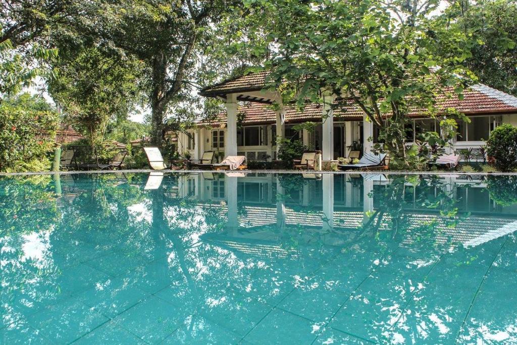 a swimming pool with chairs and a house at Plantation Villa in Kalutara