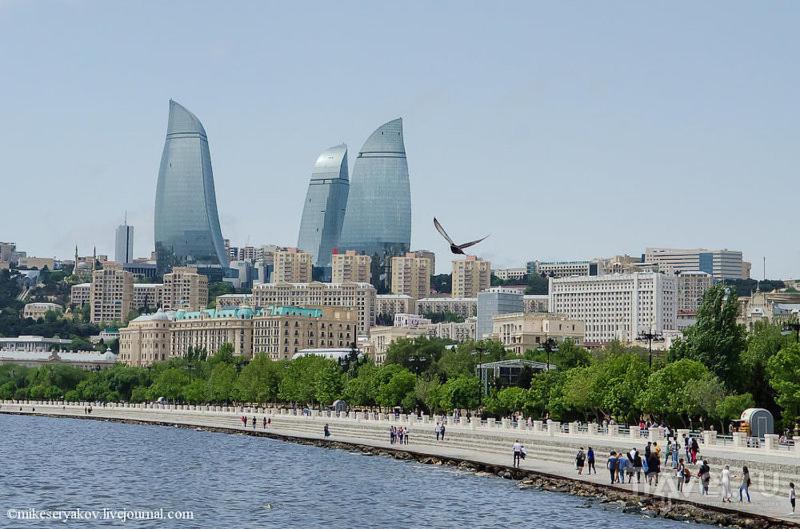 Un groupe de personnes marchant sur un trottoir à côté d'une masse d'eau dans l'établissement Guest House Tikhiy Dvorik, à Baku