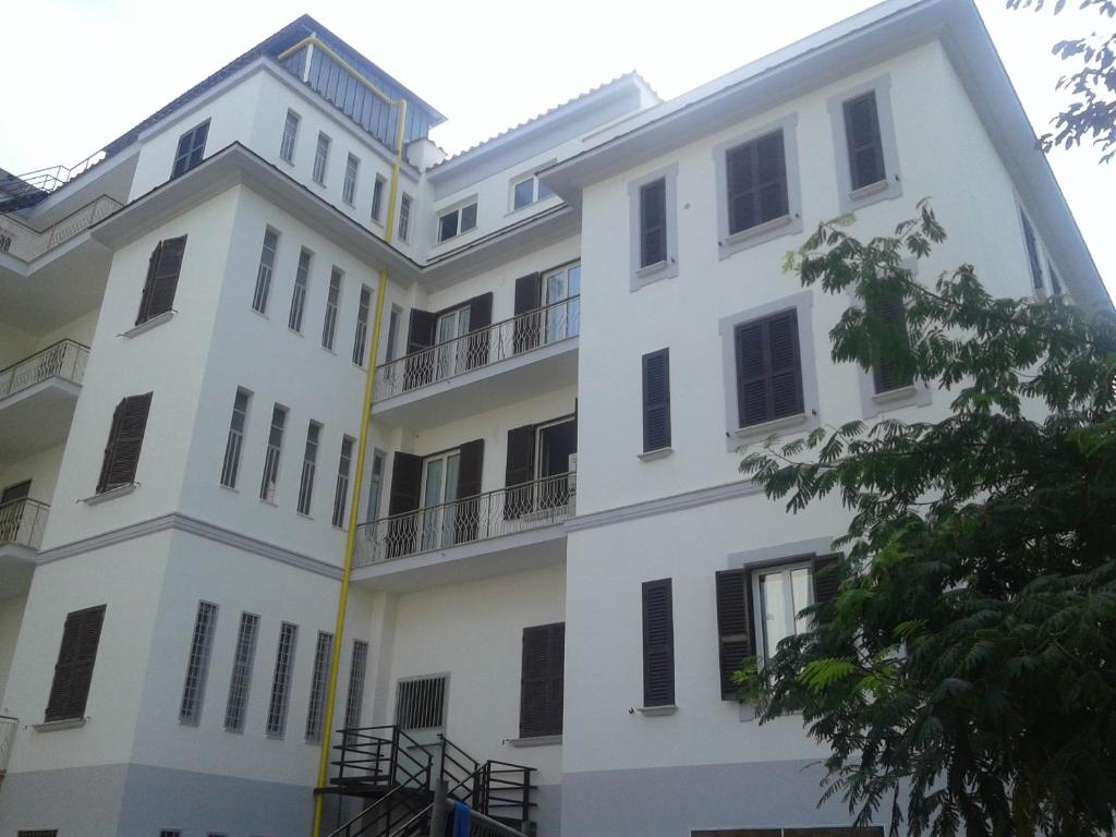 a white building with black windows and a tree at Ostello Villa Monte Mario in Rome