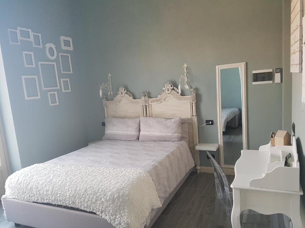 1 dormitorio con cama blanca y espejo en L'Ortodellerose, en Alba