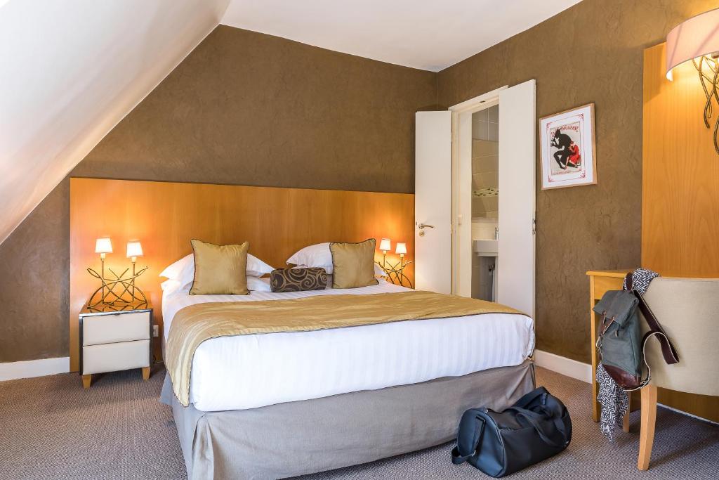 een slaapkamer met een groot bed met een houten hoofdeinde bij Hotel Boronali in Parijs