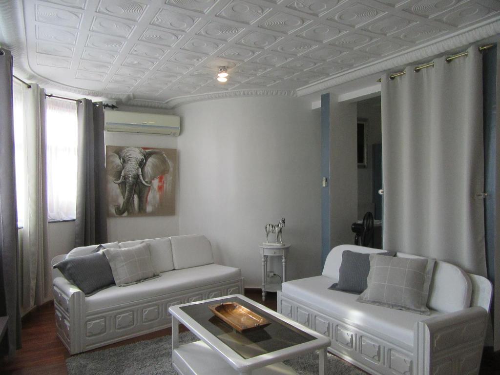 a living room with two white couches and an elephant painting at Hotel Le Griffon in Abidjan