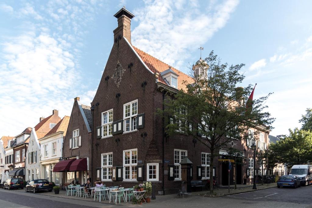 a large brick building with a tower on a street at Vesting Hotel Naarden in Naarden