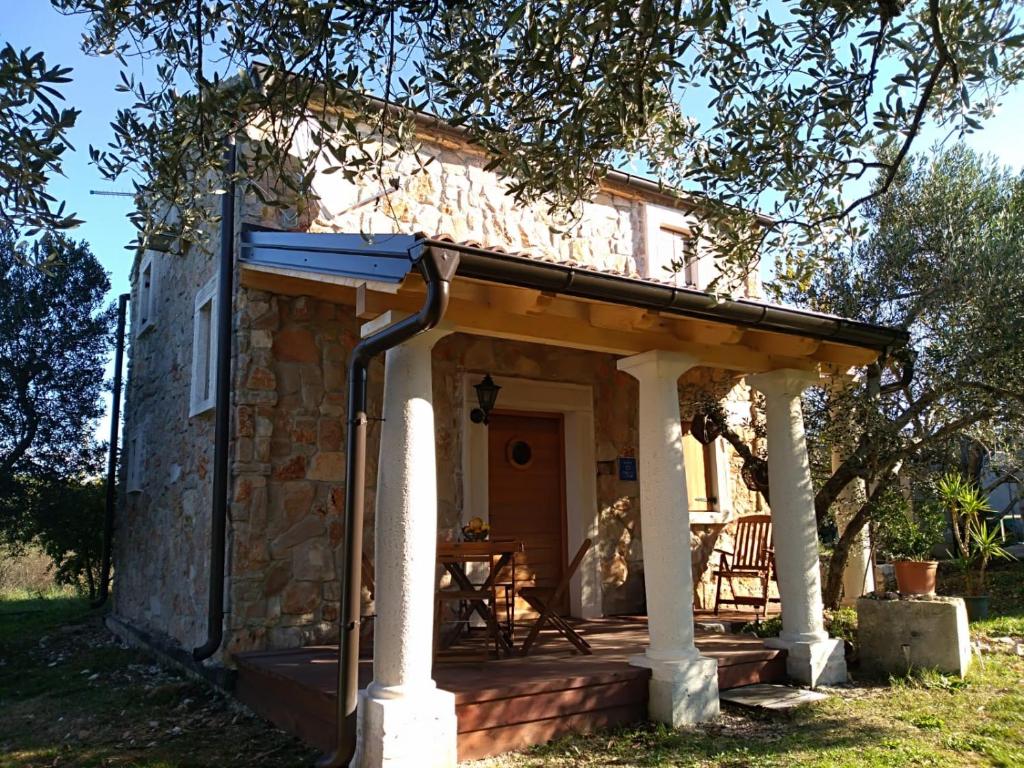 ein Steinhaus mit einer Veranda und einem Tisch in der Unterkunft Villa Flaveico in Pašman