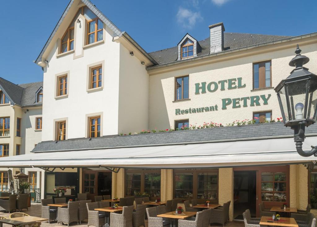 a hotel with tables and chairs in front of it at Logis Hotel-Restaurant Petry in Vianden