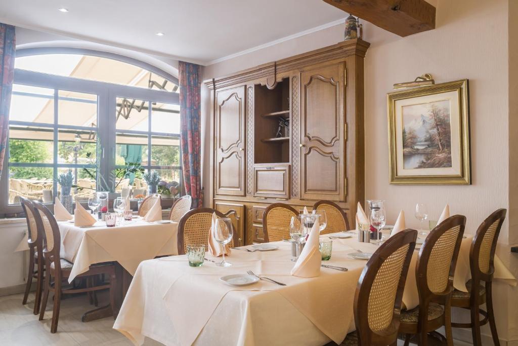 a restaurant with white tables and chairs and a window at Logis Hotel-Restaurant Petry in Vianden