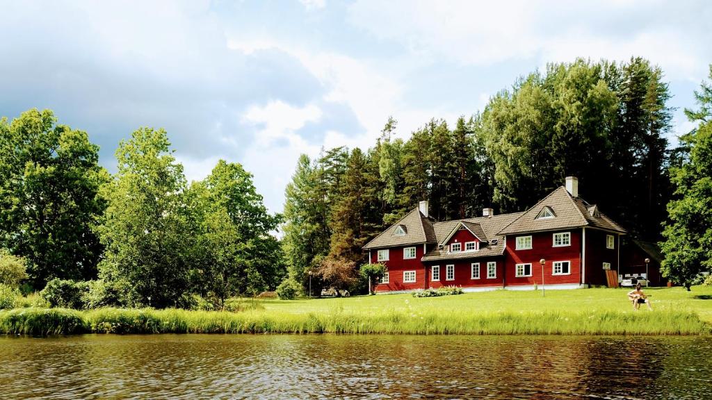 une maison rouge sur le côté d'un lac dans l'établissement Pähni külalistemaja, à Rõuge