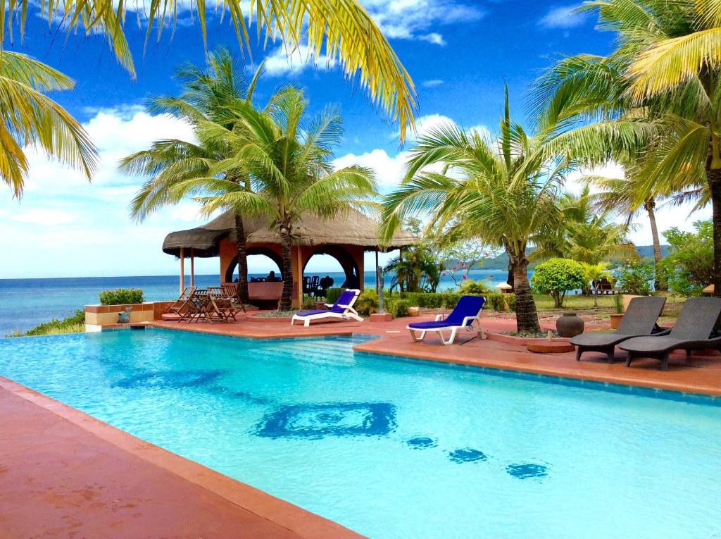 a swimming pool with chairs and a gazebo at M Villa’s Farm Resort in Romblon