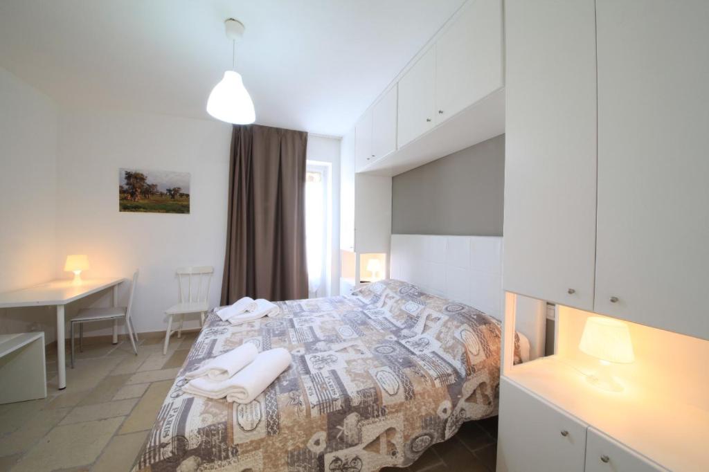 ein Schlafzimmer mit einem Bett, einem Schreibtisch und einem Tisch in der Unterkunft DIMORA AMALFITANA in Monopoli