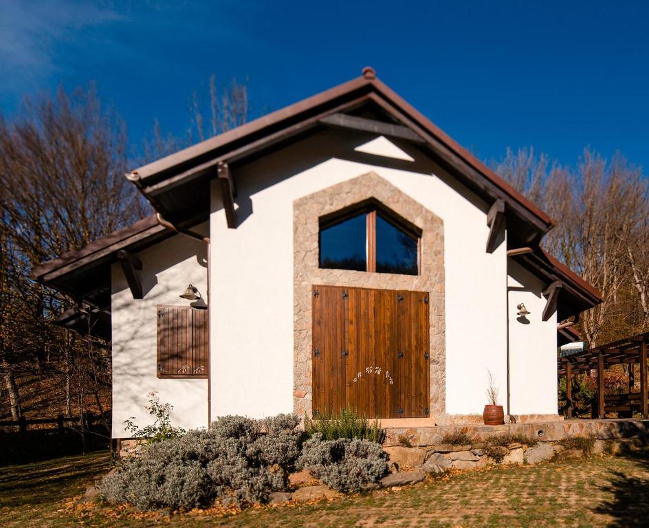 a small white house with a wooden door at Villa MontePalazzo Valiug - 1 km from Ponton Casa Baraj in Văliug