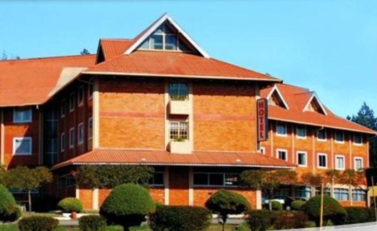 a large brick building with a red roof at Hotel Fraiburgo in Fraiburgo