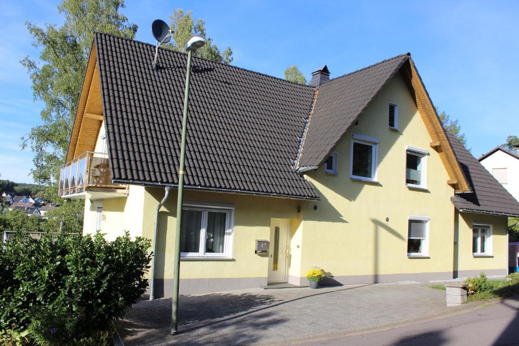 una casa amarilla con techo negro en Ferienwohnung in der Natur en Drolshagen