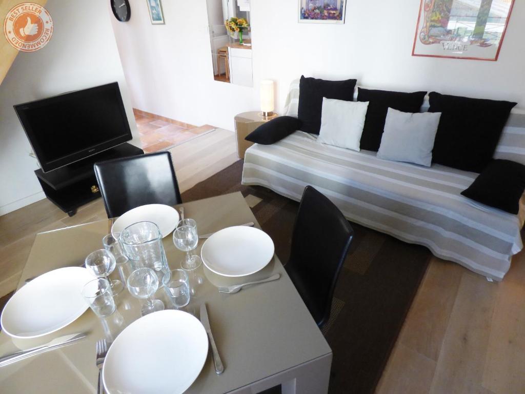 sala de estar con sofá y mesa con platos blancos en ALC - A523 - 4 min Palais and Beaches, en Cannes