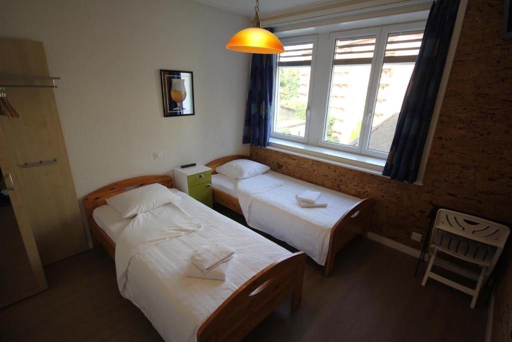 two beds in a small room with a window at Hotel Abaca in Vevey