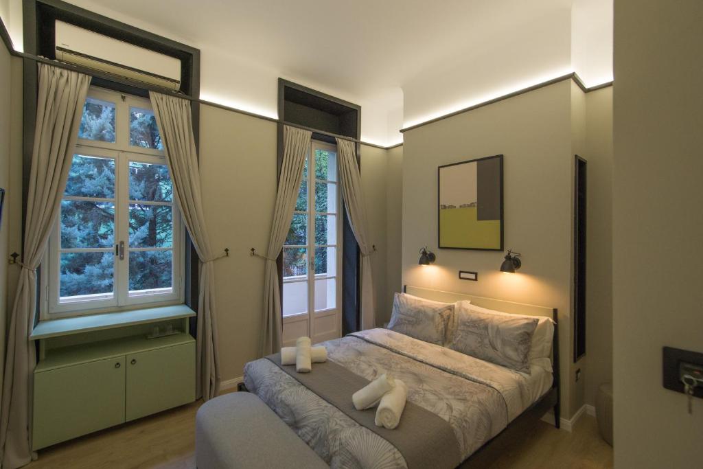 a bedroom with a bed and two windows at Destil B&B in Tirana