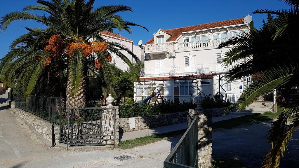 a white building with a palm tree in front of it at Apartments Srijemsi in Mlini