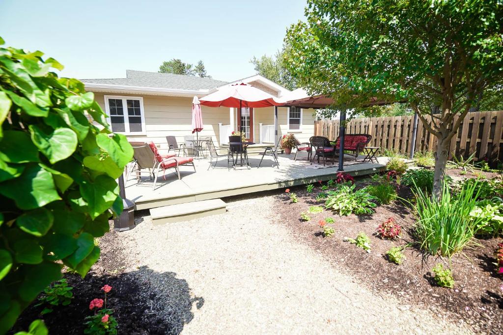a backyard with a deck with chairs and an umbrella at The Lakehouse Inn Geneva in Geneva-on-the-Lake
