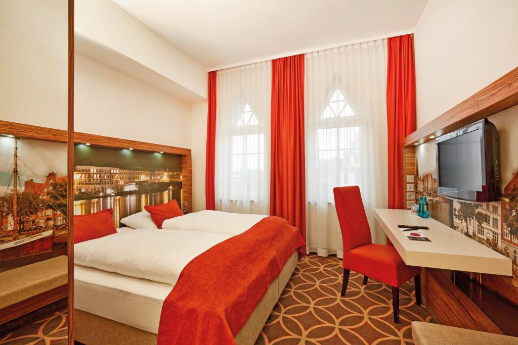 a hotel room with a bed and a desk and a tv at H+ Hotel Lübeck in Lübeck