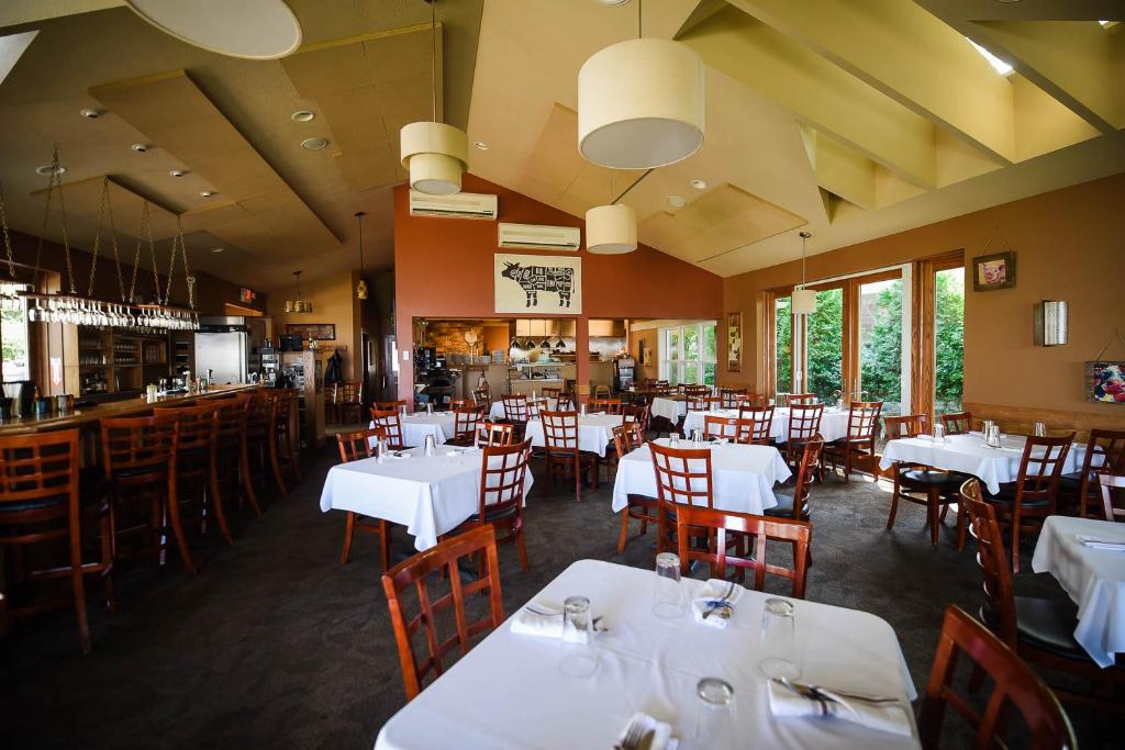 a dining room with white tables and chairs at The Lakehouse Inn Geneva in Geneva-on-the-Lake