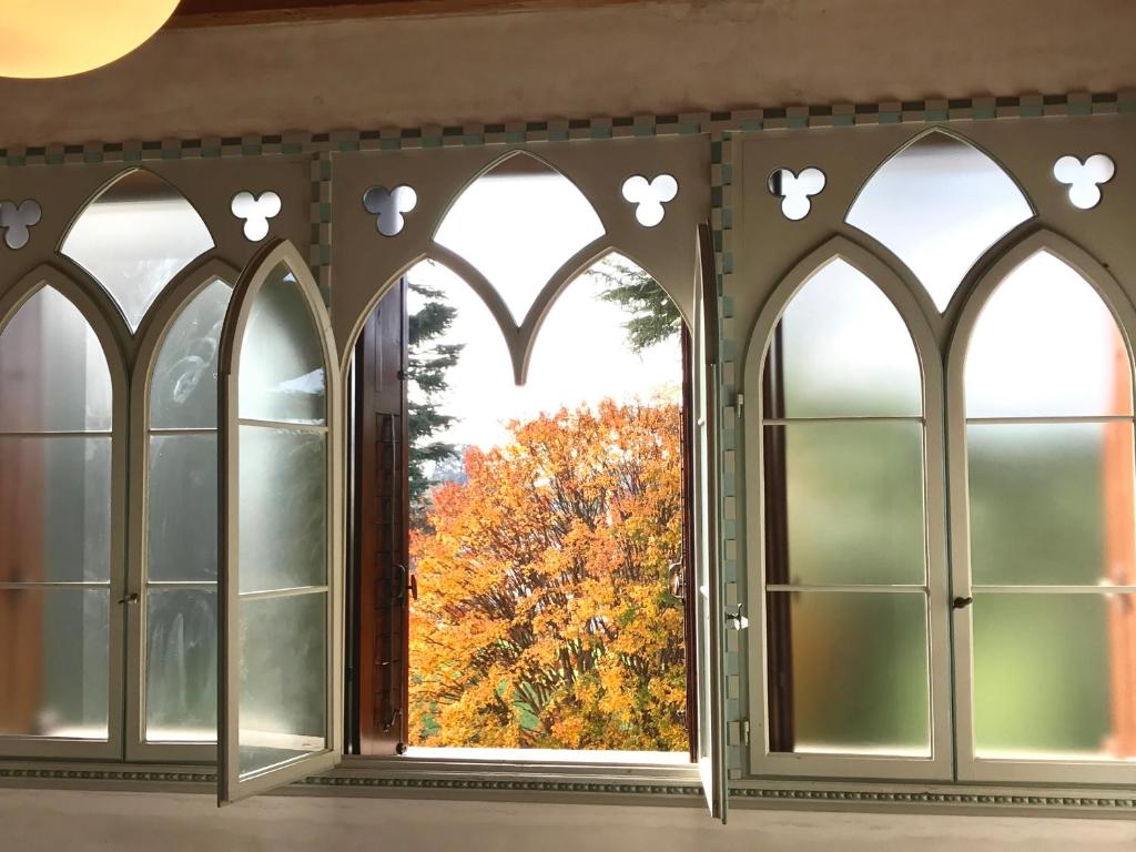 uma janela arqueada com uma árvore de outono vista através dela em Il Selese em Monticello Conte Otto