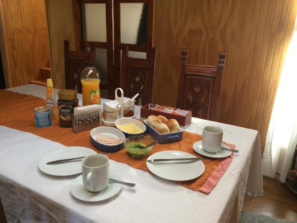 une table avec des assiettes et des tasses blanches et de la nourriture dans l'établissement Donde Damaris, à Punta Arenas