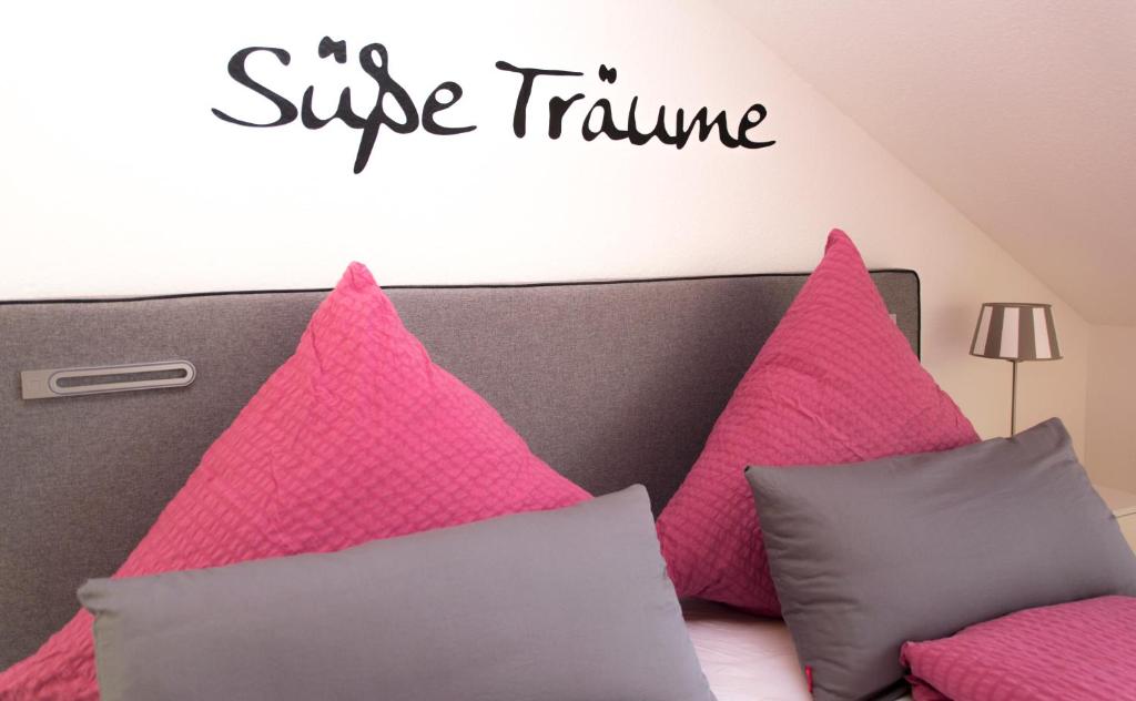 een bed met roze kussens en een bord met een groot trauma bij Ferienwohnung Schneckental in Pfaffenweiler
