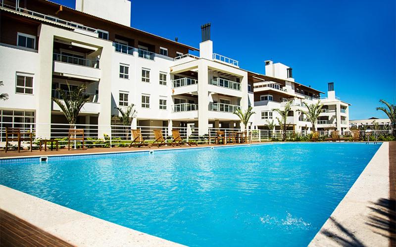 a swimming pool in front of a large building at Melhor Condomínio Villas no Campeche in Florianópolis