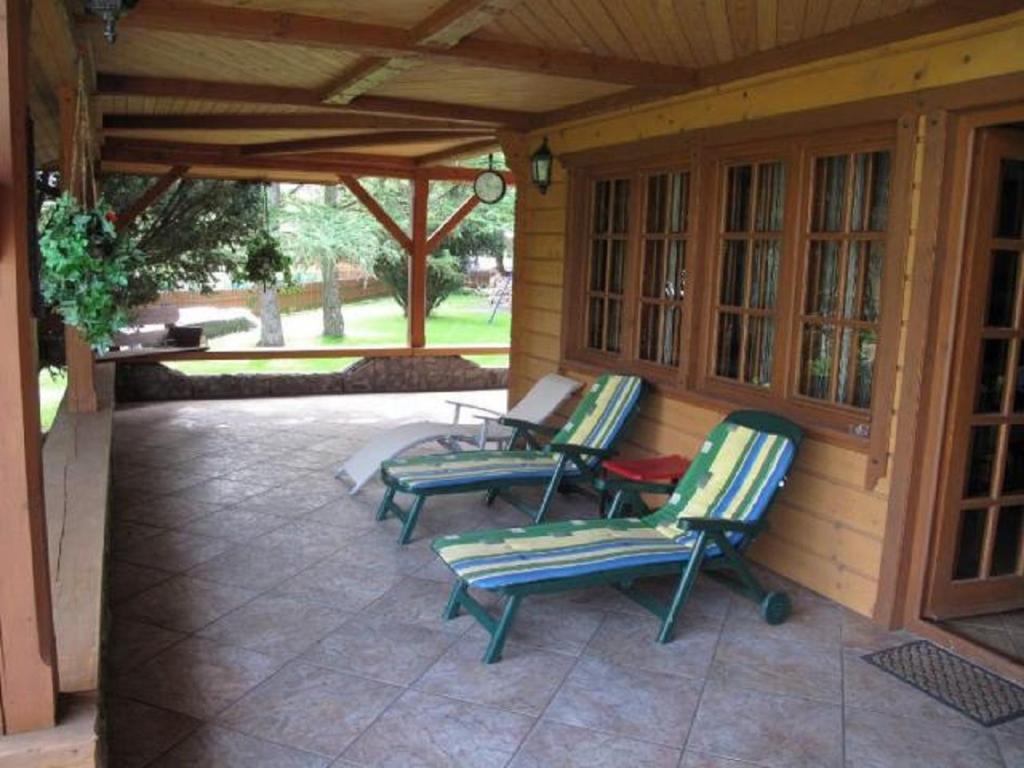 patio z 3 krzesłami ogrodowymi i werandą w obiekcie Szypry - wakacyjny dom nad jeziorem w mieście Barczewo