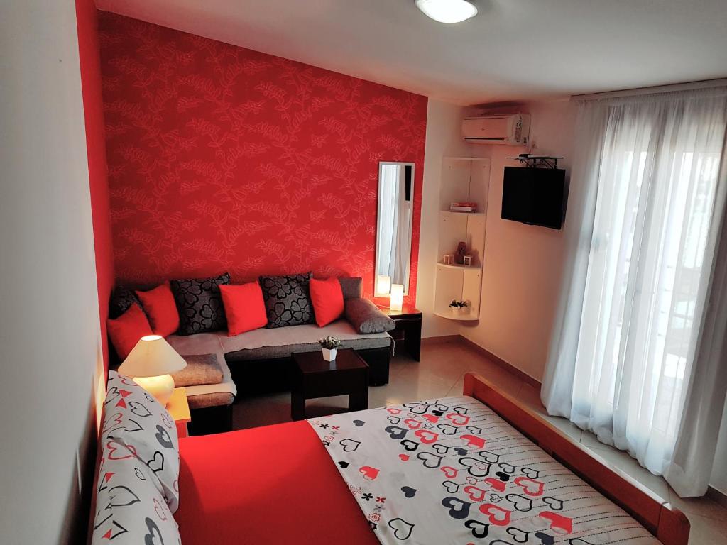 Habitación roja con cama y sofá en Apartments Taida en Dobra Voda