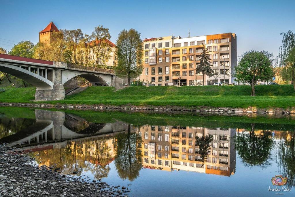 een reflectie van een gebouw in het water met een brug bij River Side Residence nr 15 in Oświęcim