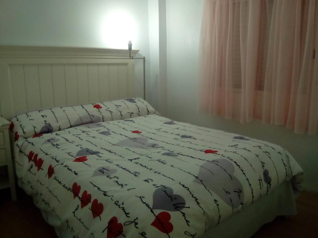 a bed with a blanket with red flowers on it at Apartamentos pandiellos I in Madrid