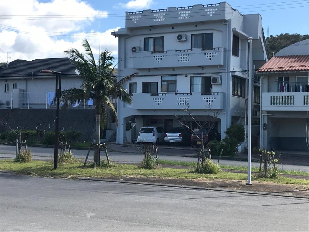 a white building with a palm tree in front of it at Takana in Nago