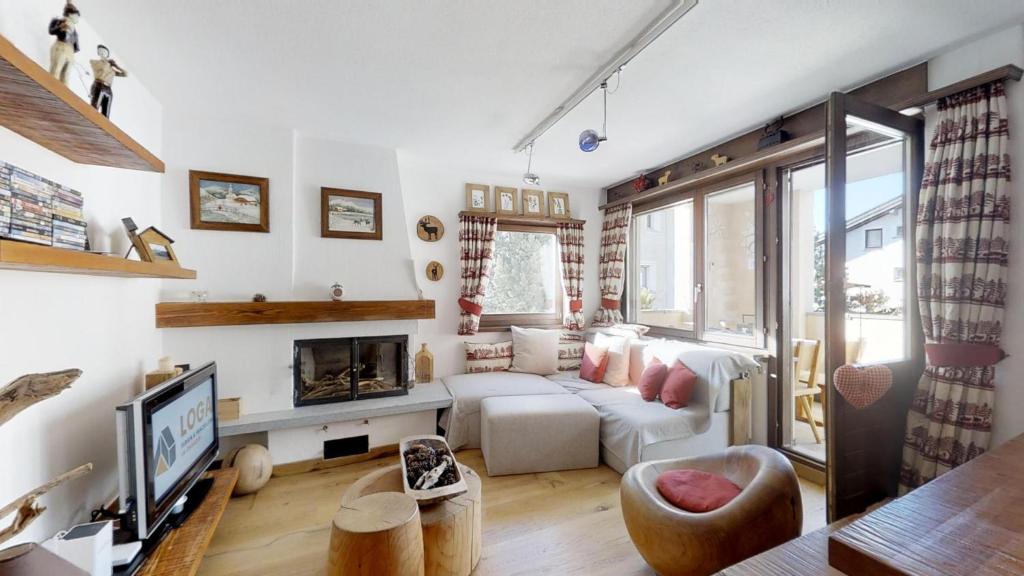 sala de estar con sofá blanco y chimenea en Murtel 4 - Sils-Maria en Sils Maria