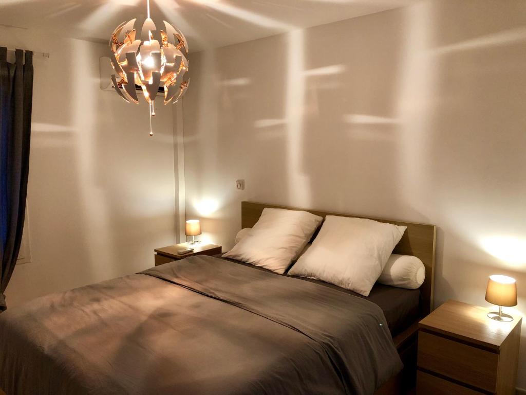 1 dormitorio con cama y lámpara de araña en Appartement Au Bord de l'Eau, en Le Moule