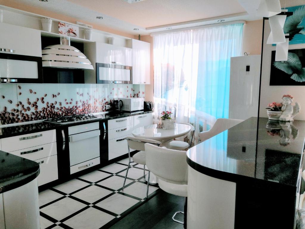 イヴァノヴォにあるАпартаменты класса Люксの白いキャビネットと黒と白のタイルフロアのキッチン