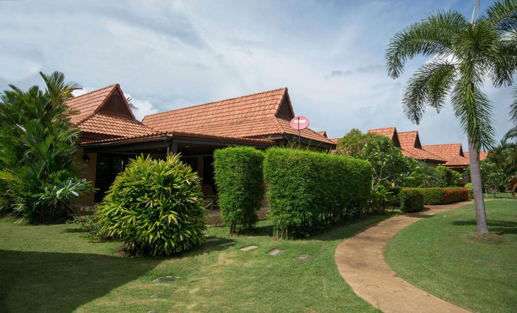 a house with a garden and a palm tree at Family-friendly house, a few steps from the pool and close to the ocean. in Mae Pim