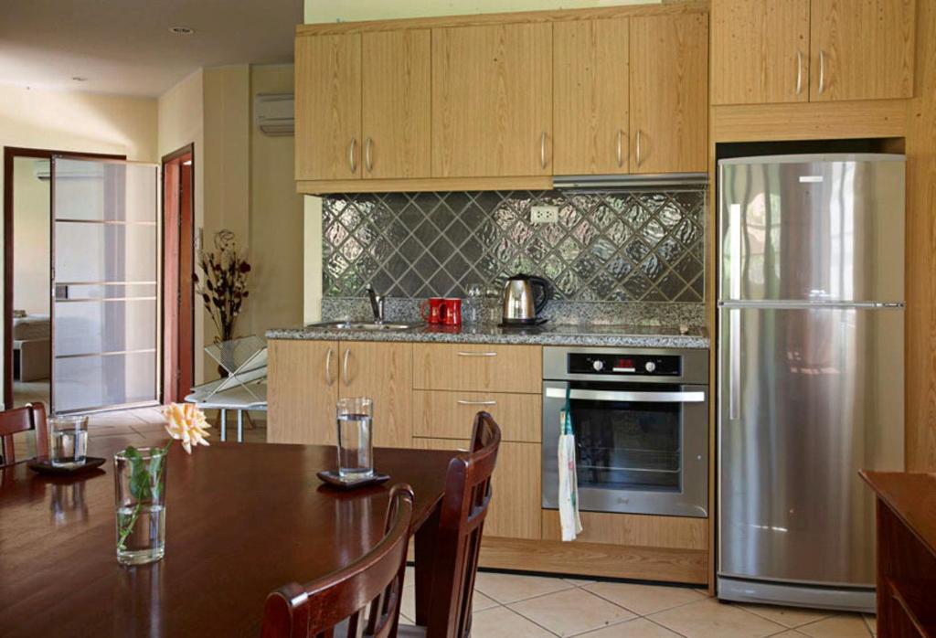 a kitchen with a table and a stainless steel refrigerator at Family-friendly house, a few steps from the pool and close to the ocean. in Mae Pim