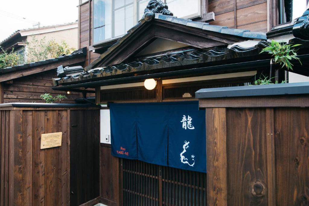 une porte menant à une maison avec un panneau bleu dans l'établissement Ryu TABI-NE, à Kanazawa