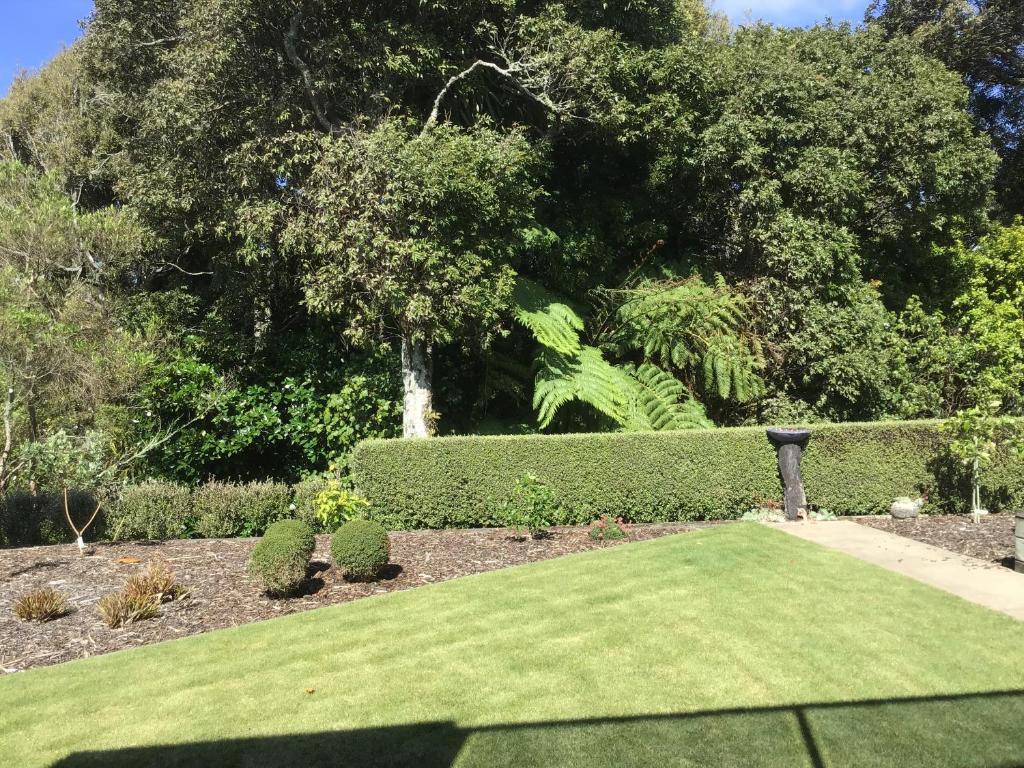 a garden with a hedge and a green lawn at Treetops On Heta in New Plymouth