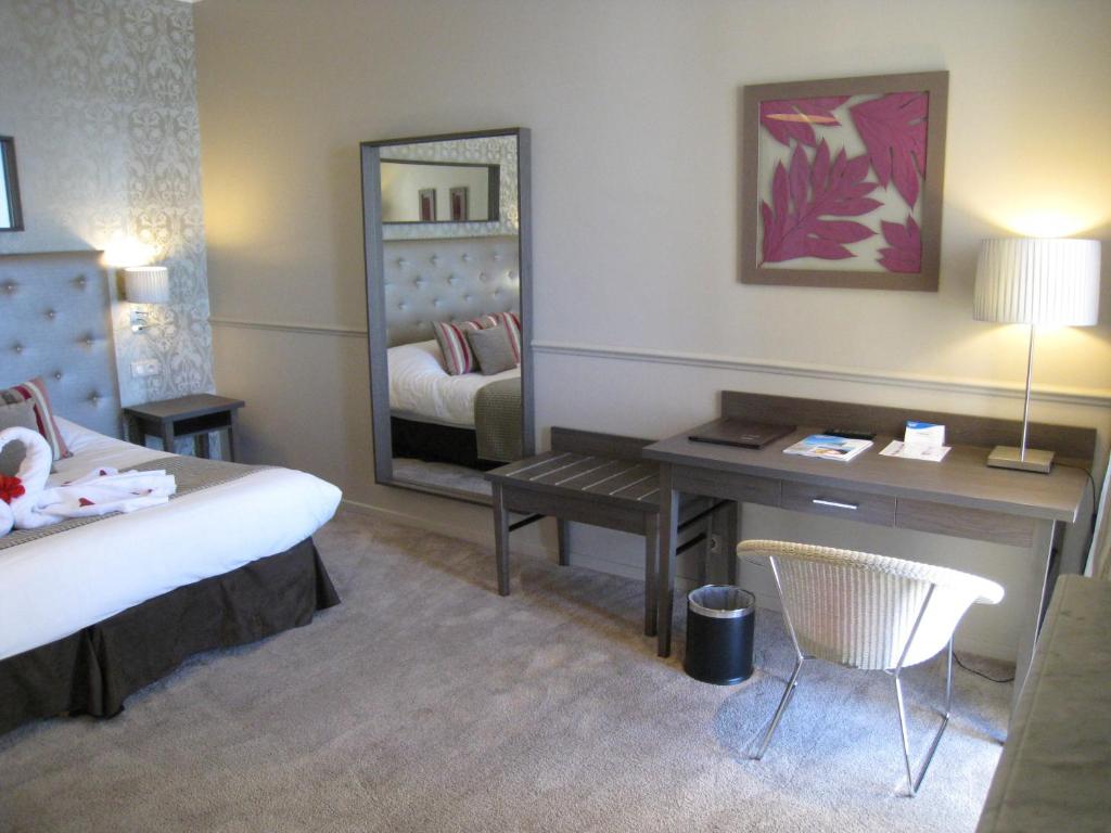 a bedroom with a bed and a desk and a mirror at Hôtel Le Royal Promenade des Anglais in Nice