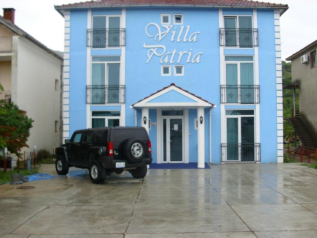 une jeep noire garée devant un bâtiment bleu dans l'établissement Vila Patria, à Podgorica