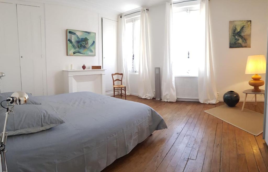 a white bedroom with a bed and two windows at Maison de Marie in Pont-Sainte-Maxence