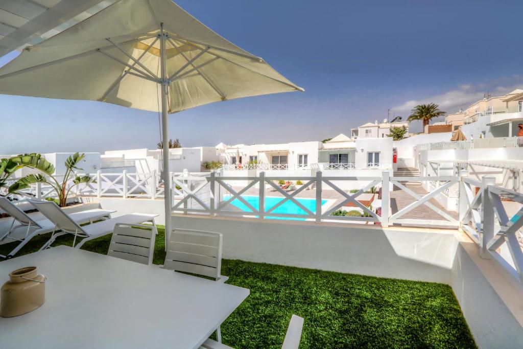 een witte tafel en stoelen met een parasol bij Flower Beach Suite 1 in Playa Honda